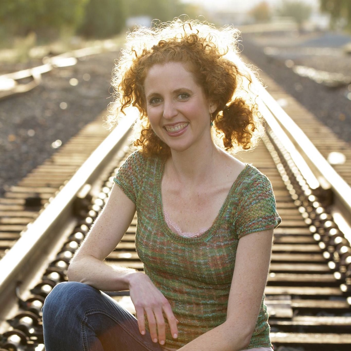 Carolyn Arnold smiling while seated on railway tracks
